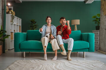 Obraz premium Excited couple cheering while watching football game on tv at home
