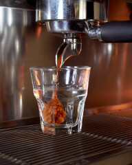 Espresso being poured into a transparent glass of water, captured at the perfect moment when the coffee forms a dramatic swirl inside the cup.