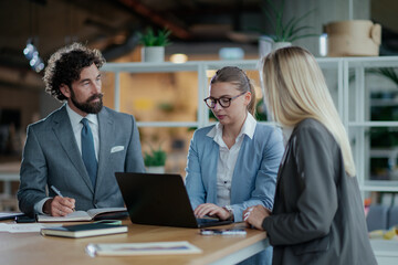Business team working together on laptop in modern office