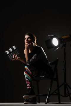 Female movie director. Girl holding clapperboard on set.