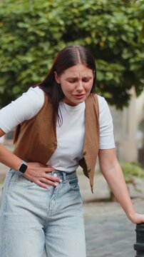 Caucasian young woman traveler feeling sudden strong abdominal stomach ache gastritis problem. Upset tourist lady having symptom poisoning diarrhea indigestion peptic ulcer pancreatitis on city street