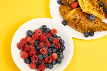 Flaky Croissant with Fresh Berries and Banana on Vibrant Yellow