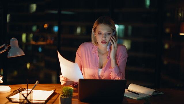 Dissatisfied executive talking smartphone holding papers in night office closeup - Powered by Adobe