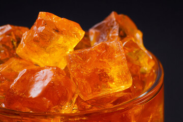 Bright orange ice cubes in a glass bowl create a refreshing visual contrast against a dark background