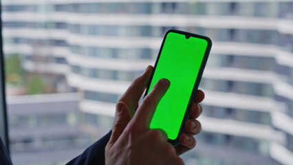 Boss browsing app green screen mobile phone standing at panoramic window closeup