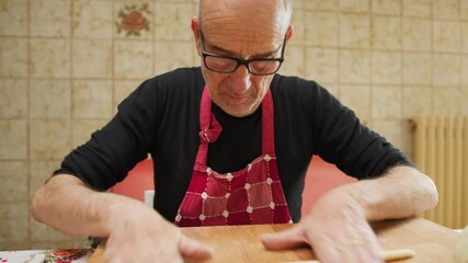 Elderly Man Works Raw Dough in the Morning in the Kitchen  - Powered by Adobe