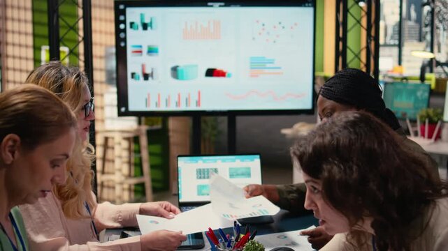 Goals oriented businesswomen dive deep into financial reports, leveraging graphs and indicators of corporate data to guide next strategic move with confidence. Company management. Camera A. - Powered by Adobe