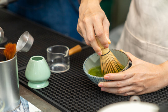Small business entrepreneur coffee shop cafe restaurant. Asian woman barista preparing matcha green tea drink on bar counter. Female waitress working part time job serving beverage to customer.