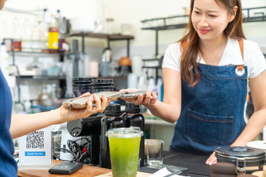 Small business entrepreneur barista coffee shop cafe restaurant. Customer using credit card on smartphone app making online banking payment buy beverage at cashier counter. Cashless payment technology