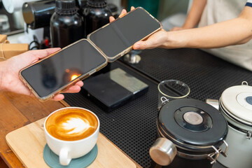 Small business entrepreneur barista coffee shop cafe restaurant. Customer using credit card on smartphone app making online banking payment buy coffee at cashier counter. Cashless payment technology.