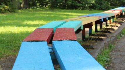 blue-red-green-yellow wooden bench on the playground with grass in the background