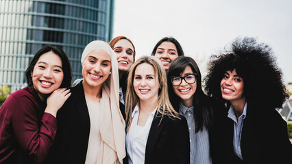 Diverse group of businesswomen smiling with office buildings on background