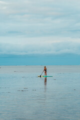 Woman paddleboarding on calm lagoon waters in Moorea, French Polynesia.