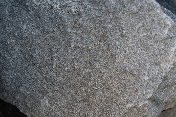 Detailed surface of rough grey granite stone with visible grain and natural texture. Suitable for backgrounds, geology projects, or material references.
