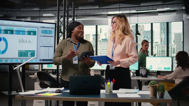 Diverse women professionals focus on report writing and analytics in office, showcasing empowerment through goals and determination for success in a competitive work environment. Camera A.