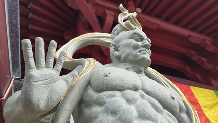Singapore - 5 July 2025. Guardian figure at Buddha Tooth Relic Temple in defensive pose, with chiseled form and flowing gold accents.