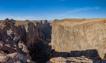 A view of a rugged canyon landscape under a clear blue sky.