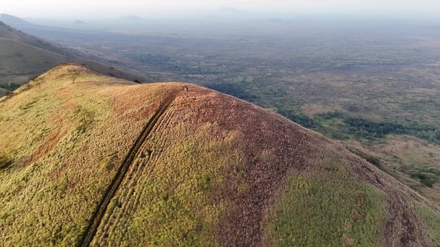 Top-down view of a grassy hill trail curving toward a summit in Chyulu Hills National Park, Kenya