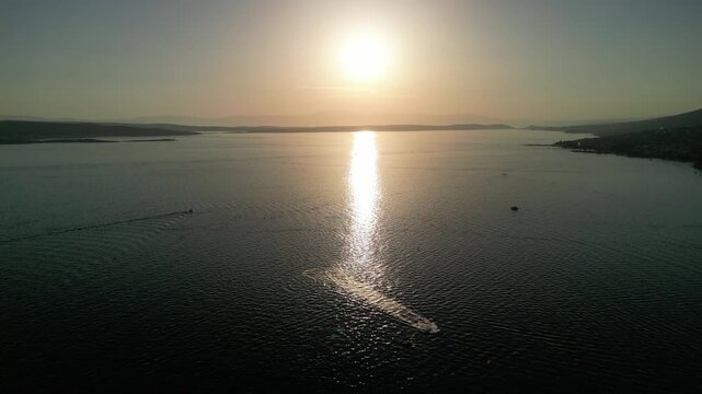 Aerial view of the calm Adriatic Sea reflecting golden sunset light near the coast of Selce, Croatia