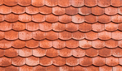 Red decorative tiles on the facade of a house, close-up texture.
