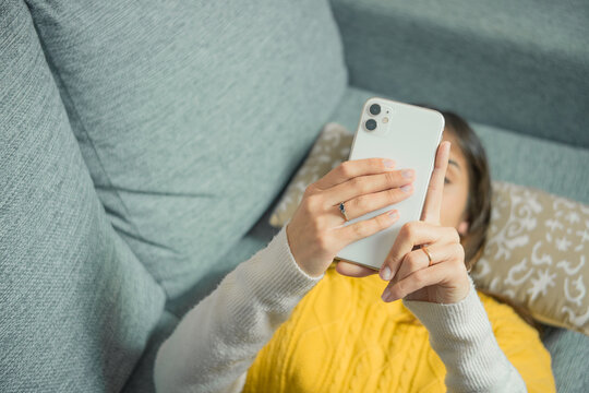 Portrait of an attractive Latina woman lying on the couch using her smartphone. People and devices concept.