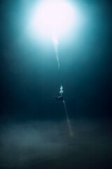 Diver illuminates the dark depths of a mysterious underwater cavern.