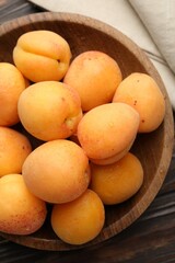 Fresh apricots in bowl on wooden table, top view