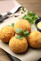 Delicious fried croquette balls with parsley on wooden table, closeup