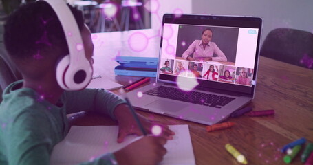Taking notes child wearing headphones at home table, using laptop grid and notebook, copy space