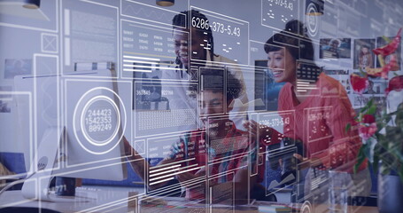 Collaborating team analyzing data visuals at office desk, with monitor, stylus and chart overlays