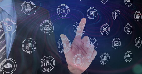 Businessman wearing suit and tie interacting with touch interface in workspace and floating icons