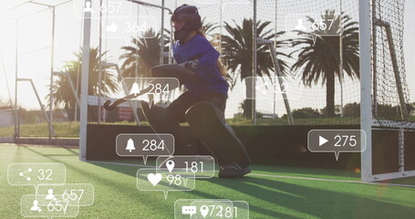 Kneeling teenage goalkeeper holding hockey stick wearing helmet on hockey turf, with social icons