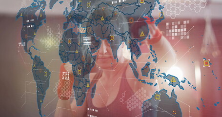 Punching woman wearing sports bra and red gloves at gym, with world map hex pattern overlay
