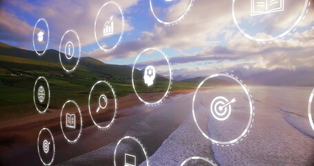 Obraz premium Floating cluster of digital icons moving over sunset beach, with business education symbols
