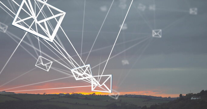 Fototapeta Spanning white envelope icons and connecting lines over farmland hills at sunset, showing network