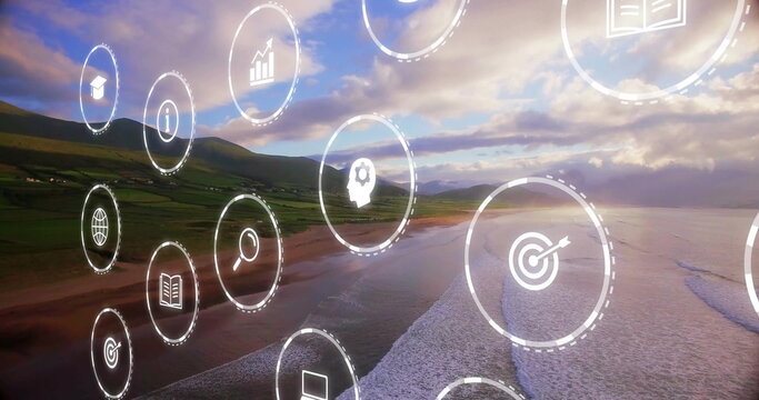 Floating cluster of digital icons moving over sunset beach, with business education symbols