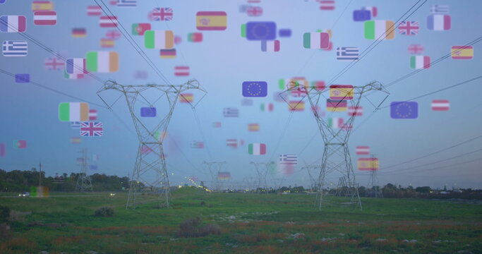 Displaying steel lattice towers carrying power lines across grassland at dusk, with European flags
