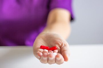 Doctor offering red and white pills in open hand