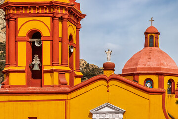 Colorful colonial church with bell tower and dome in Bernal, Mexico, with Peña de Bernal in the background