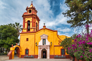 Fototapeta premium Colorful chapel with bell tower and cross in Bernal, Mexico