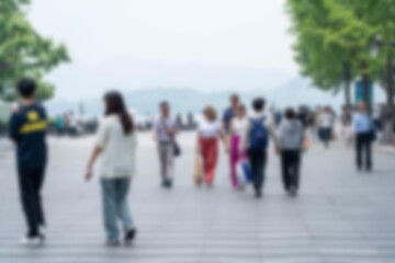 A group of people walk down a blurred sidewalk in Hangzhou, China.