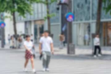 A blurred image of two people walking down a street in Hangzhou, China.