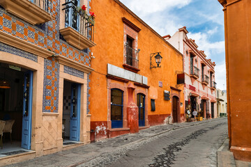 Orange colonial building with blue doors and balconies on cobblestone street in Bernal, Mexico