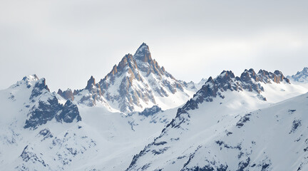 Obraz premium Majestic snow covered mountain peaks piercing the sky under a bright cloudy day
