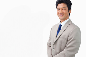 Asian man standing and smiling in photography studio wearing beige suit and blue tie, copy space