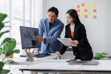 Two asian business man Asian woman using tablet ipad, standing near the window in workplace	
