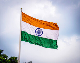 Indian national flag waving in the sky. The tricolor flag features saffron, white, and green horizontal stripes with the blue Ashoka Chakra wheel in the center. Symbol of patriotism, unity, and Indian
