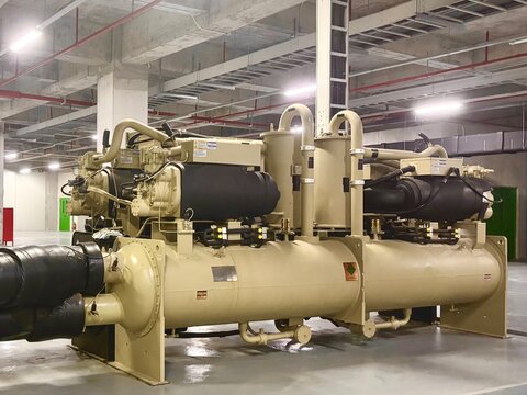 Industrial chiller system in a factory building. Large air conditioning and cooling units used in HVAC for temperature control in manufacturing or commercial environments.
