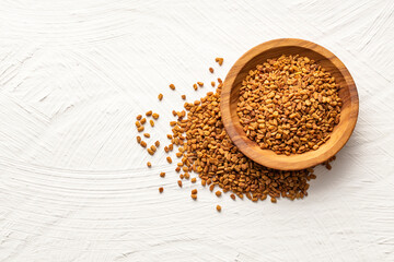 Dried organic fenugreek seeds in the wooden bowl - Trigonella foenum - graecum