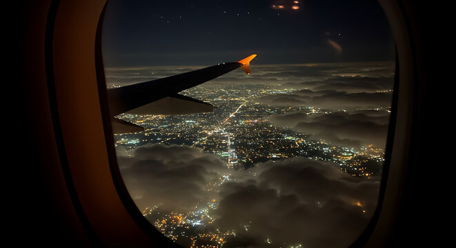 Breathtaking aerial view of a sprawling illuminated city from an airplane window during a nighttime journey.